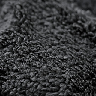 Close-up of Fox Legwarmers' black textured fabric, featuring soft, plush fibers in different directions. The image emphasizes the cozy and luxurious surface of the legwarmers.
