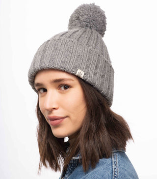 A woman wearing a handmade Park Fold Rib Pom Beanie made of merino wool.