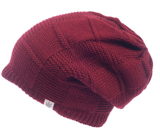 A maroon wool Checkered Slouch hat with a textured pattern is shown. The handmade in Nepal beanie features a small tag with a logo sewn onto the brim. Photographed against a plain white background, it showcases its craftsmanship beautifully.