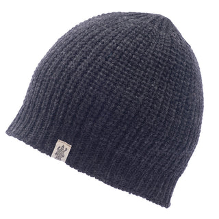 The Cardigan Knit Beanie, handcrafted in Nepal from 100% wool, is dark gray with a ribbed texture and features a small label attached to the lower edge. It is photographed against a white background.