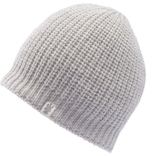 A light gray, 100% wool Cardigan Knit Beanie shown on a white background. This beanie features a waffle-like texture and a small fabric tag with a design near the bottom edge, handmade in Nepal.