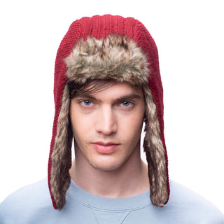 A person with light skin and blue eyes is wearing a Winter Trapper Hat with faux fur lining and ear flaps in red, looking directly at the camera. The background is white, and the person is dressed in a light blue shirt.