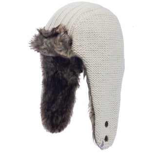 The Winter Trapper Hat features a beige wool knit design complemented by dark brown faux fur lining and ear flaps. For added charm, small round buttons adorn one of the ear flaps.