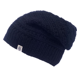 Introducing the Boho Slouch, a dark blue knit winter hat with a small white tag featuring a dark emblem on the ribbed brim. This hat boasts a textured pattern and offers a slightly slouchy fit, perfect for achieving that boho slouch look.