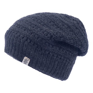 A dark blue Boho Slouch knitted beanie with a textured finish is shown in the image. This winter hat features a slouchy design and a small fabric tag with a logo on the ribbed cuff, perfect for adding a touch of bohemian style to your look.
