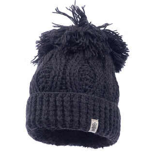 Handmade in Nepal, the Big Pom Rib Fold Hat is crafted from 100% merino wool. It showcases a black knitted design featuring an intricate cable pattern, a large pom-pom on top, and a ribbed fold-over brim. The front is accented with a small tag displaying the logo.