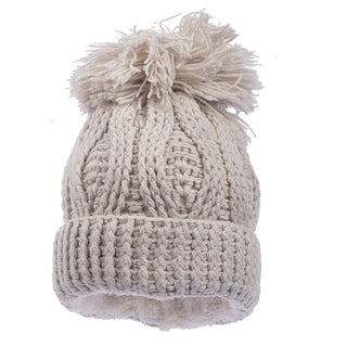 Introducing the Big Pom Rib Fold Hat: a beige, knitted winter hat featuring a large pom on top and a thick rib fold brim. This hat is handmade in Nepal from 100% merino wool and boasts a cable-knit pattern crafted from soft, chunky yarn.