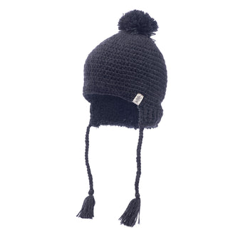 The Verona Earflap Hat, crafted from black wool and handmade in Nepal, is adorned with a pom-pom on top and features braided tassels hanging from both earflaps. A small tag is attached to the side of the hat.