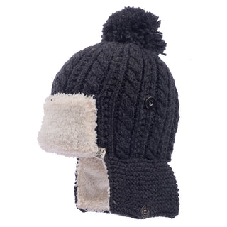 The Sherpa Trapper Hat w/ Pom, handmade in Nepal, is displayed. This black knit hat comes with a fluffy white merino wool lining, a pom-pom on top, ear flaps, and a button closure under the chin for extra warmth and coverage.