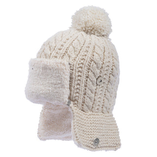 The Sherpa Trapper Hat w/ Pom is a beige hat featuring ear flaps, a pom-pom on top, and a cable knit pattern. Handmade in Nepal from merino wool, it includes two buttons on the ear flaps that are lined with soft, fuzzy material for added warmth.