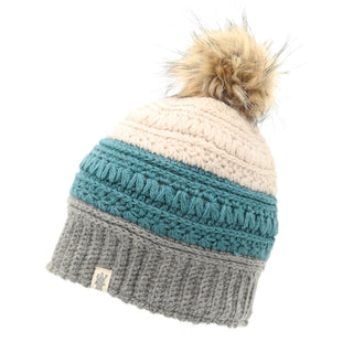 Introducing the Stripe Flower Fur Pom Pom: a stylish Merino wool hat with a ribbed grey bottom, a textured teal middle section, and a beige top. This chic winter accessory is topped with a fluffy fur pom-pom and features a small logo label on the grey portion.