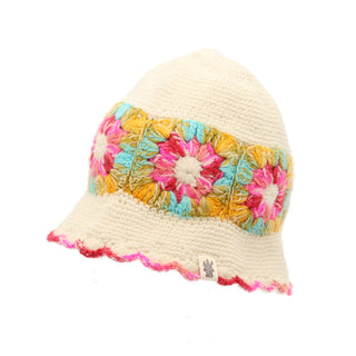 Image of the Mushroom Hat, a white crochet hat featuring a colorful floral granny square pattern around the middle. The hem of this hand-knit headpiece includes red and pink crochet at the bottom edge. A small tag with an emblem is sewn on, showcasing its intricate design and craftsmanship.