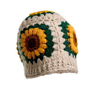 The Sunflower Hat is a handmade, cream-colored wool hat featuring large yellow, brown, and green sunflower patterns on the sides, shown against a black background.