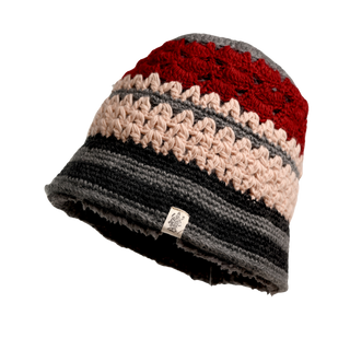 Introducing the Stripe Sun Hat: a multicolored, hand-knit beanie adorned with patterns in red, beige, and dark gray. This merino wool hat features a small white tag with an illustration, set against a black background that highlights its texture and design.
