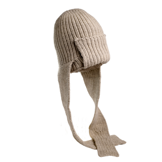 The Pelham Hat is a hand-knit beige balaclava with long, flat extensions that hang down on either side. Crafted from soft merino wool, the main body fully covers the head, extending over the forehead and possibly the neck for superior warmth. The ribbed material ensures a stretchable and snug fit.