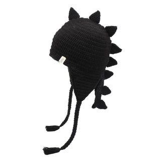 The DinoTail Hat is a black knit beanie hat featuring ear flaps and braided tassels, designed with multiple triangular spikes along the top and back to resemble a dinosaur's back.