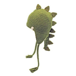 The DinoTail Hat is a green crocheted hat designed to resemble a dinosaur, featuring triangular spikes along the top and back, as well as braided tassels hanging from the earflaps. The background is plain white.
