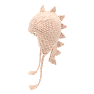 The DinoTail Hat is a beige crocheted hat designed to resemble a dinosaur. It features several triangular spikes running along the top and back, and long braided tassels hanging from both sides.