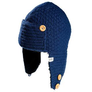 The Elk Hat is a blue knitted winter hat featuring ear flaps, a ribbed texture, and soft lining at the ear flaps. It includes three tan buttons—one on the front flap and two on the sides—for added style.