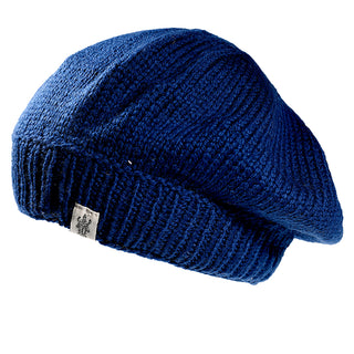 The Abbey Hat is a blue knit beret with a ribbed band and a small logo tag, shown against a white background.