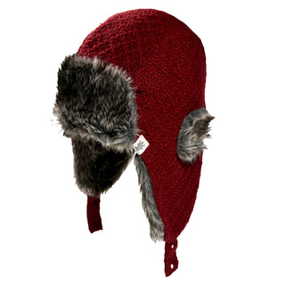 The Fern Hat is a red knit winter trapper hat with gray faux fur lining on the ear flaps and front brim, shown against a white background. It features a small white tag on the side.