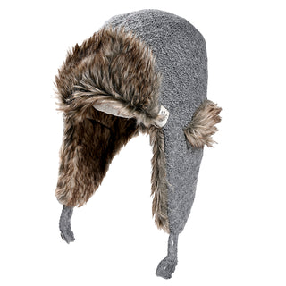 The Fern Hat is a grey winter trapper hat with faux fur lining, ear flaps, two hanging tassels, and a small fabric tag on the side.