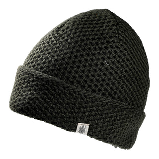 The Baltic Hat is a dark green, knitted beanie with a folded brim and a small rectangular tag featuring a black emblem, shown against a white background.