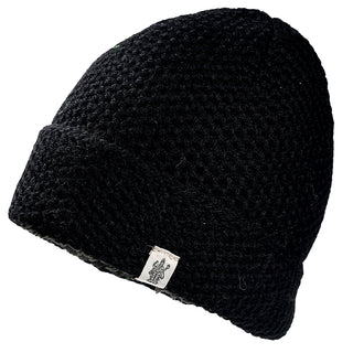 The Baltic Hat is a black, chunky-knit beanie with a folded brim and a small white logo tag attached.