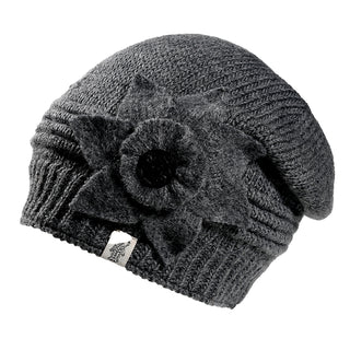 The Monroe Hat is a dark gray knit beanie featuring a large textured fabric flower on the side and a small logo tag on its ribbed brim, set against a white background.