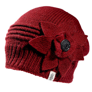 The Monroe Hat is a red knitted beanie featuring a large fabric flower with a black button center on the side, textured ribbed details, and a small white logo tag near the brim.