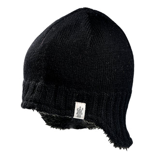 The Dakota Hat is a black knit winter hat featuring ribbed edges, ear flaps, and a small white tag with a visible logo near the brim. It is shown against a white background.