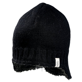 The Dakota Hat is a black knit winter hat with ear flaps, ribbed edging, and a small white rectangular tag on the lower side, displayed against a plain white background.