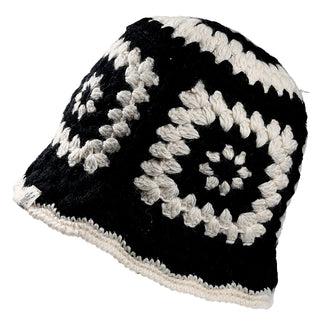 The Milie Hat is a black and white crocheted bucket hat with a repeating square pattern, geometric design, and a slightly flared brim made from alternating rows of black and white yarn.