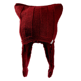 The Ezra Hat is a red knitted hat featuring pointed cat ear corners and two long, thick ear flaps on each side.