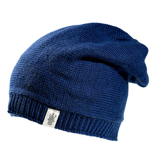 The Dekalb Slouch is a dark blue Merino wool beanie with a ribbed edge and a small white embroidered tag by the hem, designed for unisex cold-weather wear.