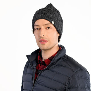 A man wearing the Cooper Hat, a red and black plaid shirt, and a black puffer jacket stands against a plain white background, looking at the camera with a neutral expression.