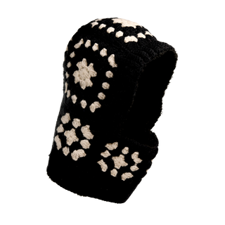 The image features the Crochet Patch Hood, a black crochet balaclava adorned with white knitted flower motifs scattered across its surface. The balaclava is displayed against a plain black background.