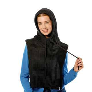 A person is wearing a dark grey Bibbed Hood layered over a light blue shirt. They are holding the drawstring with their right hand and smiling at the camera. The background is completely black.