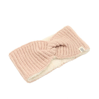 Introducing the Tuk Headband: a light pink, hand-knit accessory featuring a twisted knot design in the center. This stylish headband is crafted from soft merino wool and has a cozy white fleece lining. Displayed against a plain white background, it perfectly showcases its fashionable design.