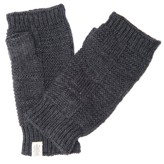 A pair of Checkered Handwarmers is displayed. The dark gray, knitted fingerless gloves, handmade in Nepal from 100% wool, feature a textured pattern and ribbed cuffs. A small white label is visible at the cuff on one of the gloves. The image is set against a plain white background.