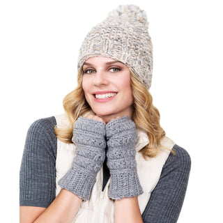 A person with curly blonde hair is smiling and wearing a grey knit hat with a pom-pom, **Starry Handwarmers**, and a grey sweater with a white vest. The background is plain white.