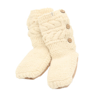 Slipper Socks with 3 Buttons are cream-colored, knitted baby booties made from 100% wool, featuring cable-knit detail. Each cozy winter bootie is adorned with three wooden buttons on the side and has a soft sole. The thick and cozy texture of the knit is reminiscent of traditional slipper socks.