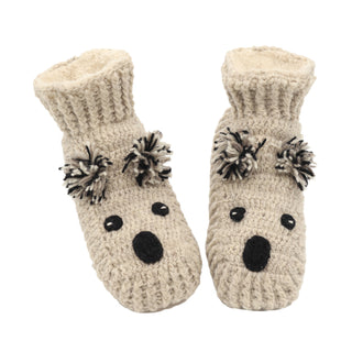 A pair of Koala Slippers designed to resemble a bear, featuring black yarn eyes, noses, and ear tufts. The slippers have a ribbed cuff and a soft, fuzzy texture. They are placed side by side with the toe sections facing forward.