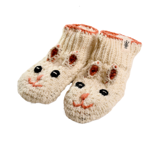 The Rabbit Slippers are a pair of knitted baby booties shaped like bunny faces, crafted from white yarn with pink accents. These cozy slippers feature embroidered eyes, a nose, and a smiling mouth, along with two small protruding ears on the front. The interior and edges are lined with pink fabric for extra comfort.
