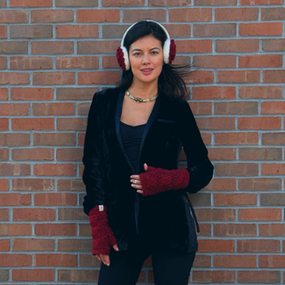 A woman wearing Camellia Earmuffs standing next to a brick wall.