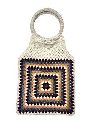 The Cotton Crochet Handbag features a round handle and a central square granny pattern in white, purple, blue, orange, and yellow. It is displayed against a plain white background.