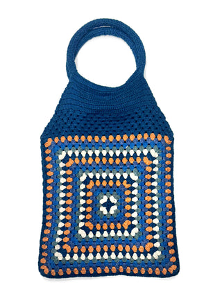 The Cotton Crochet Handbag features a square pattern in blue, orange, white, and gray with two circular handles and a solid blue upper section.