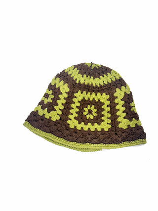 The Cotton Crochet Patch Sun Hat features a geometric pattern of green and brown granny squares, showcased on a plain white background.