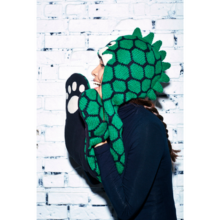 A woman wearing a green, hand-knit Dinosaur Hatscarf.