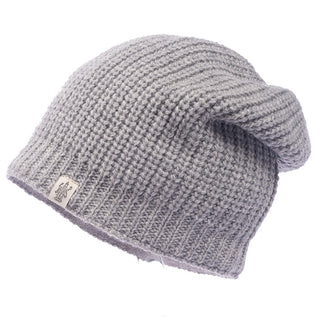 A handmade, 100% wool Cardigan knit slouch beanie in gray with a ribbed texture and small fabric tag on the edge, crafted in Nepal. Beautifully displayed against a plain white background.
